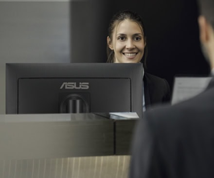 İnsanların ön büroda bilgisayar kullanırken güler yüzlü hizmet veren çalışan, çağrı merkezi veya müşteri hizmetleri personeli, müşteri memnuniyetini artırmaya odaklı profesyonel hizmet.