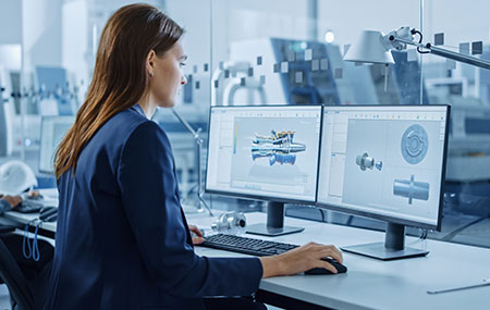 Yüksek teknolojili mühendislik ve tasarım yazılımı kullanarak bilgisayar destekli tasarım çalışmalarını yapan kadın mühendis, modern üretim ve prototip geliştirme ortamında.
