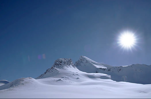Dağlar ve karla kaplı alanlar, parlak güneş ışığı altında muhteşem kış manzarası. Doğa tutkunları ve kış fotoğrafçıları için ideal görüntü.